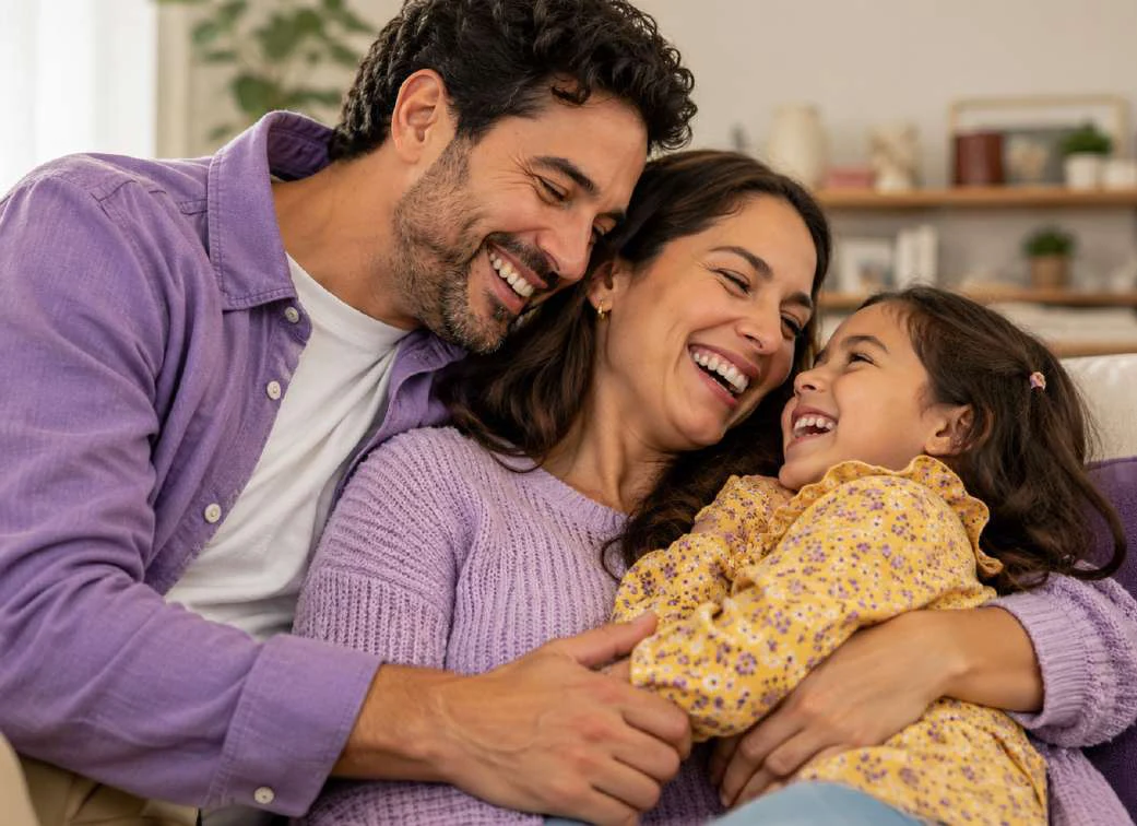 Familia abrazándose y riendo en casa